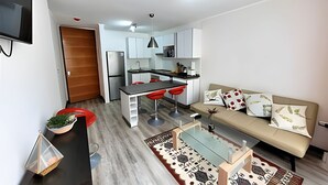 Une cuisine moderne avec des meubles blancs, un réfrigérateur et des tabourets de bar rouges.