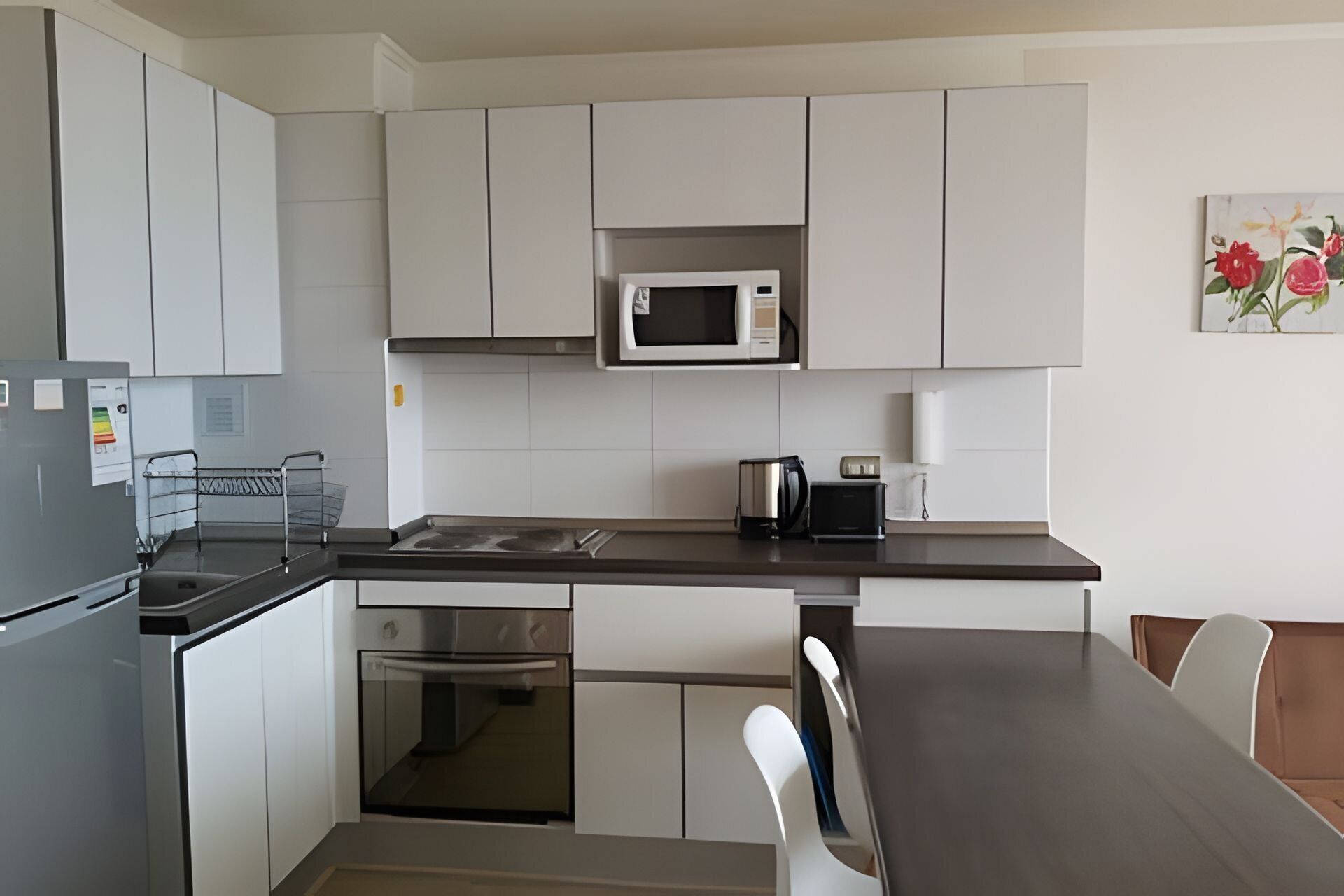 A modern kitchen with white cabinets, a microwave, a kettle, and a toaster.