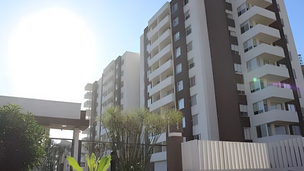 A multi-story residential building with balconies, large windows, and a clear sky.