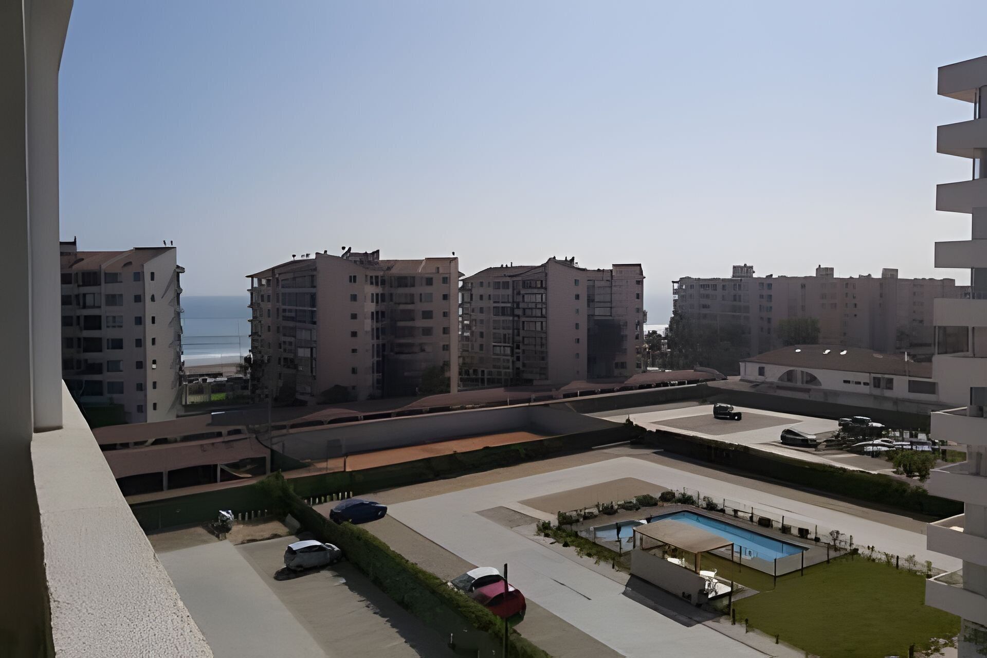 Zona residencial con varios edificios de apartamentos, una piscina y un estacionamiento.