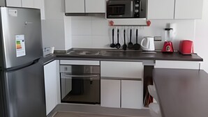 A modern kitchen with white cabinets, a stainless steel refrigerator, a microwave, and a coffee maker.