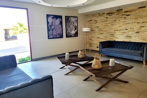 Ein modernes Wohnzimmer mit einem blauen Sofa, zwei Holztischen und einer Steinwand.