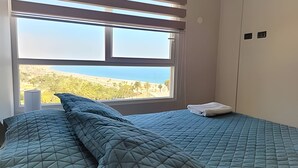 Une chambre à coucher avec un lit, une fenêtre donnant sur un beau paysage et une armoire.