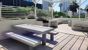 Une terrasse extérieure avec une table et des bancs, entourée d’une structure de pergola blanche.