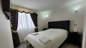 A bedroom with a bed, a nightstand, a wall-mounted light, and a window with curtains. - Dept. 7th Floor, Pacífico III (La Serena)