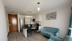 A modern apartment with a kitchenette, dining area, and a living room with a blue sofa. - Dept. 7th Floor, Pacífico III (La Serena)