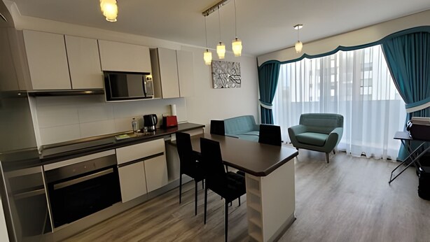 A modern kitchen with a microwave, coffee maker, and a dining area with a table and chairs. - Dept. 7th Floor, Pacífico III (La Serena)