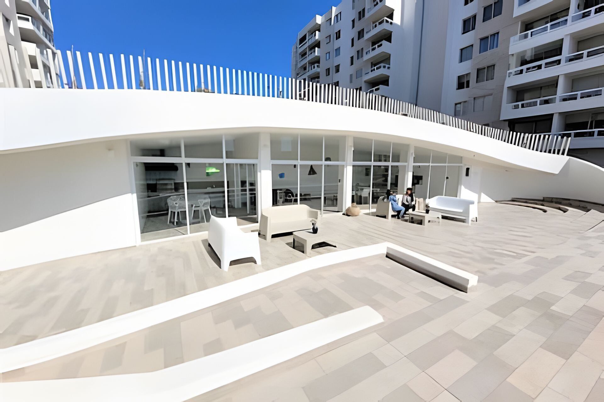 A modern building with a curved facade, large glass windows, and outdoor seating areas.