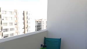 Un balcon avec une table ronde, une chaise et un pot de fleurs.