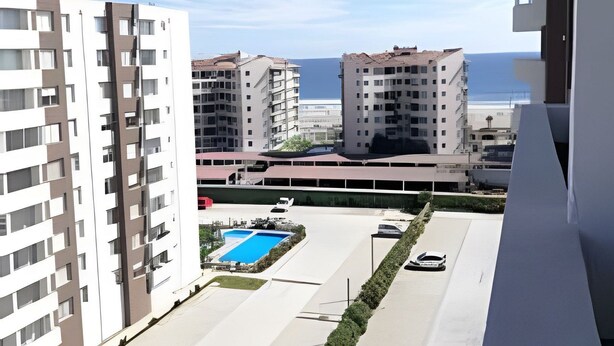 Un immeuble résidentiel doté d’une piscine, d’un parking attenant et offrant une vue sur la mer.