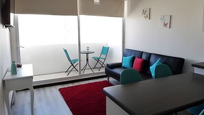 Un salon moderne avec un canapé, une table à manger et un petit balcon équipé de chaises.