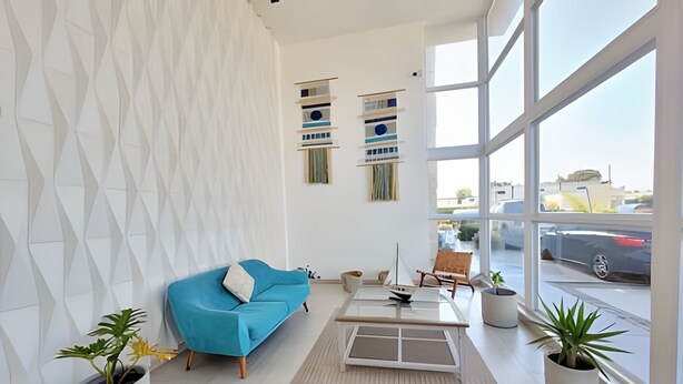 A modern living room with a blue sofa, a coffee table, and potted plants. - 5th-floor apartment in a condo. Pacific 2800 (La Serena)