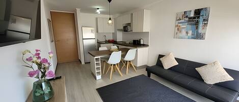 A modern apartment with a dining area, kitchen, and living room.