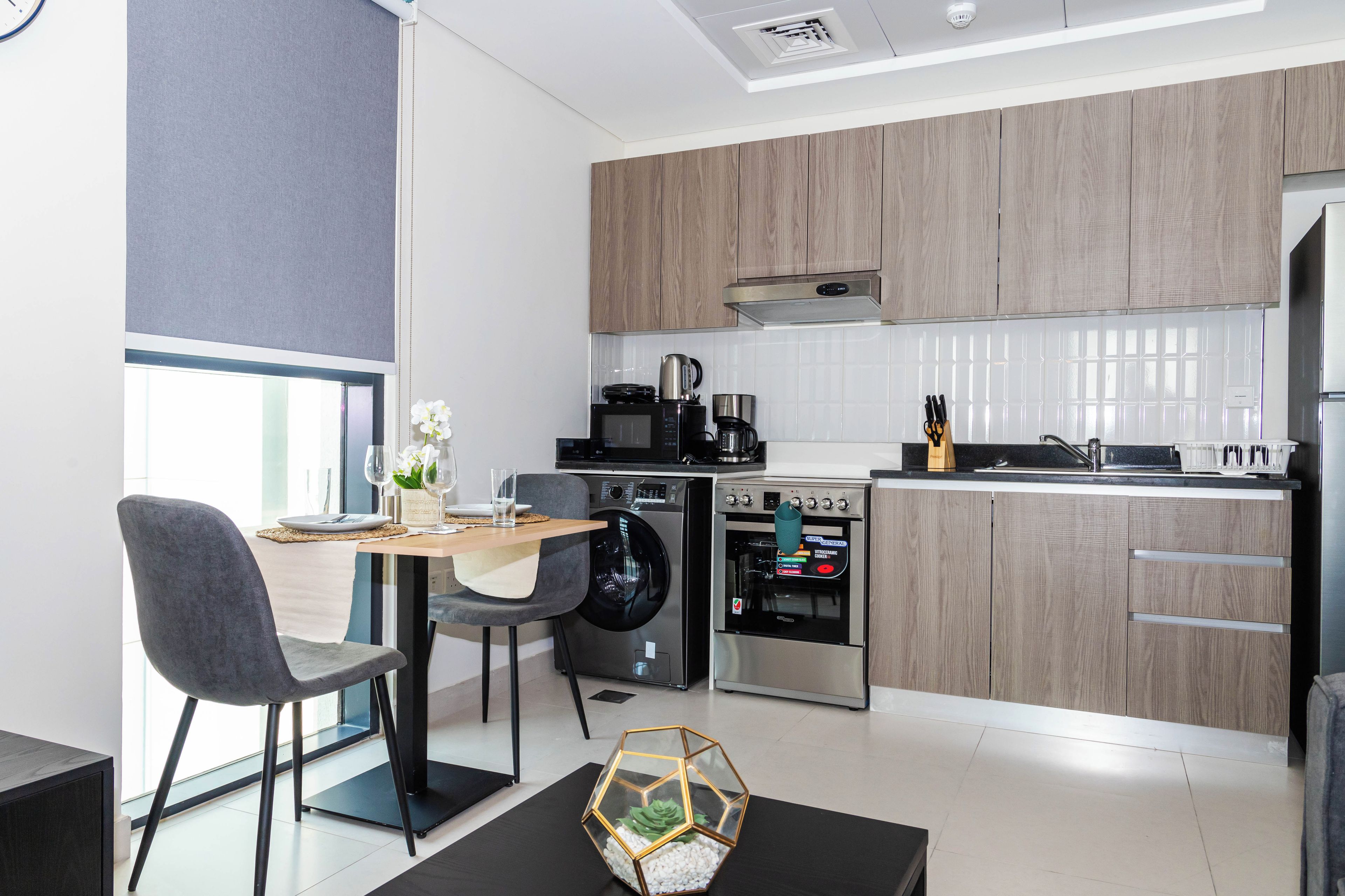 Una cocina moderna con comedor, que incluye una mesa con sillas, lavadora y cafetera.