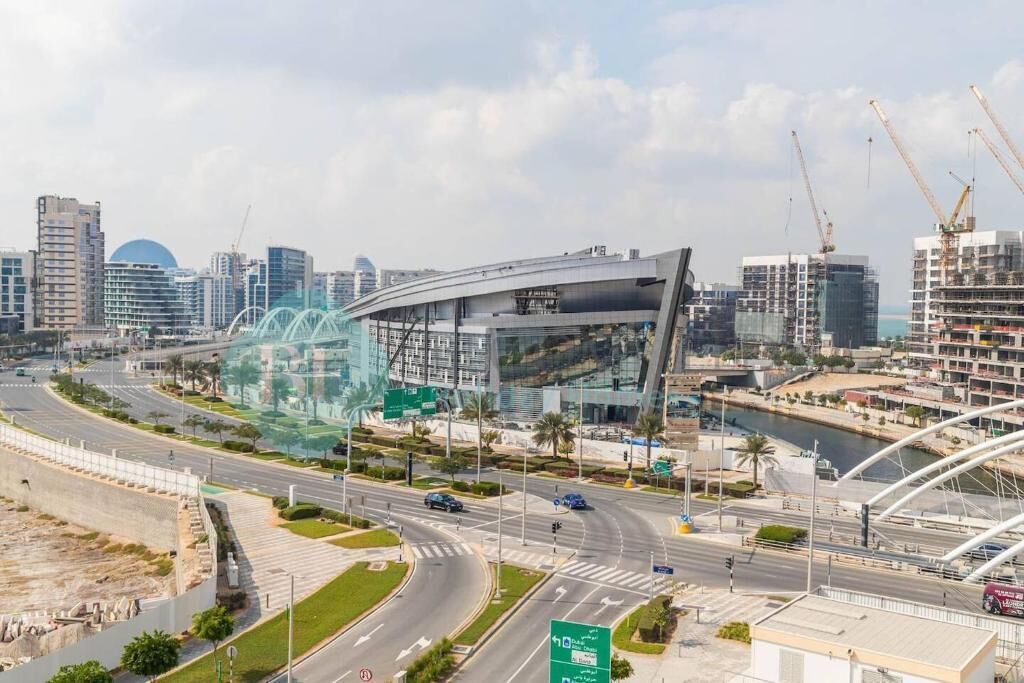 Un moderno paisaje urbano con un edificio curvo destacado, un río y un puente.