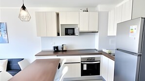 Eine moderne Küche mit weißen Schränken, einer Holz Arbeitsplatte, einer eingebauten Mikrowelle und einem Kühlschrank.