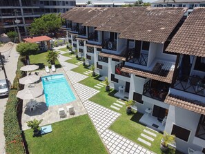 Ein mehrstöckiges Hotel mit Pool, Sitzgelegenheiten im Freien und einem gepflegten Garten.