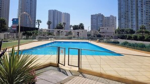 A swimming pool with a tiled deck, surrounded by tall residential buildings. - Dept. 14th Floor, Marina Costa (Coquimbo)