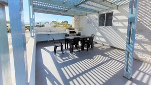 En uteplats med grill, sittplatser och en pergola.