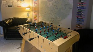 Una habitación con una mesa de fútbol de mesa, un mapa en la pared y un sofá.