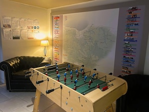 Una habitación con una mesa de futbolín, un mapa en la pared y un sofá.