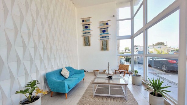 A modern living room with a blue sofa, a coffee table, and potted plants. - Apartment, 8th floor, Pacífico 2800 (La Serena)