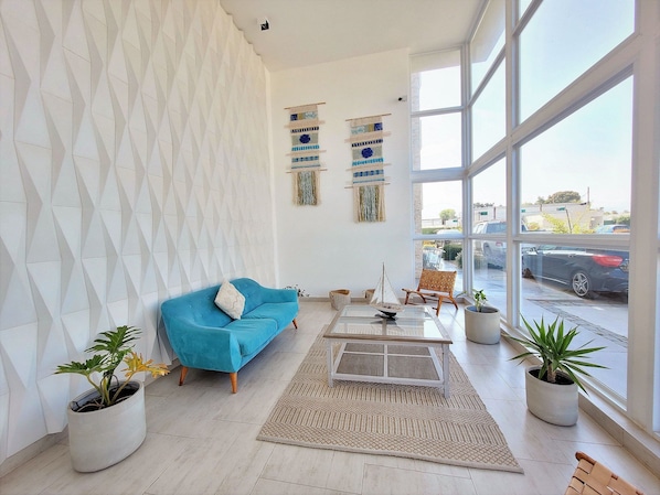 A modern living room with a blue sofa, a coffee table, and potted plants.