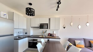 A modern kitchen with white cabinets, a microwave, and a dining area with a long table and chairs. - Apartment, 8th floor, Pacífico 2800 (La Serena)