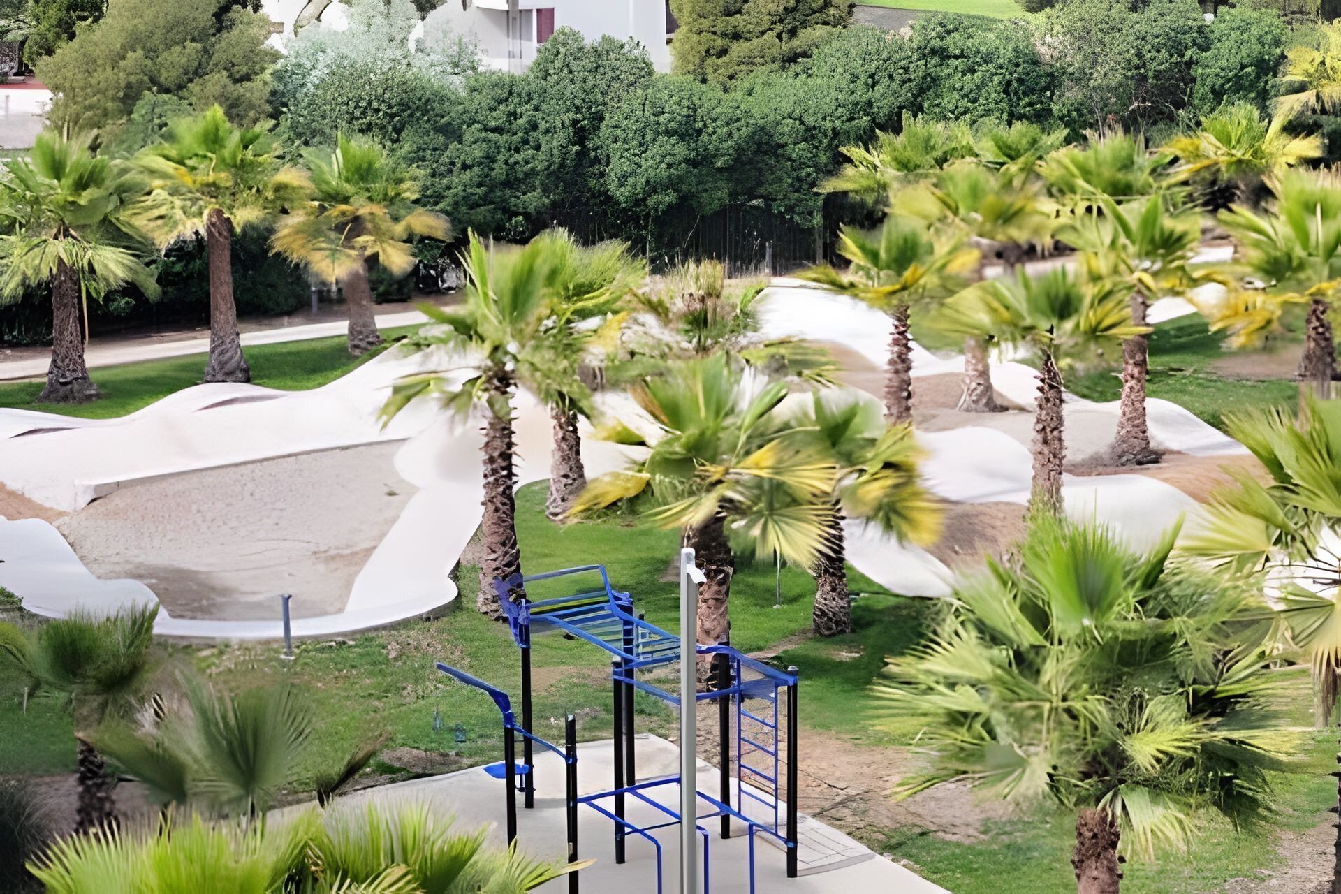 A playground with palm trees and a blue climbing structure.