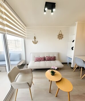 A modern living room with a sofa, chairs, a small table, and decorative wall art. - Dept. 5th Floor, Distrito Verde (La Serena)