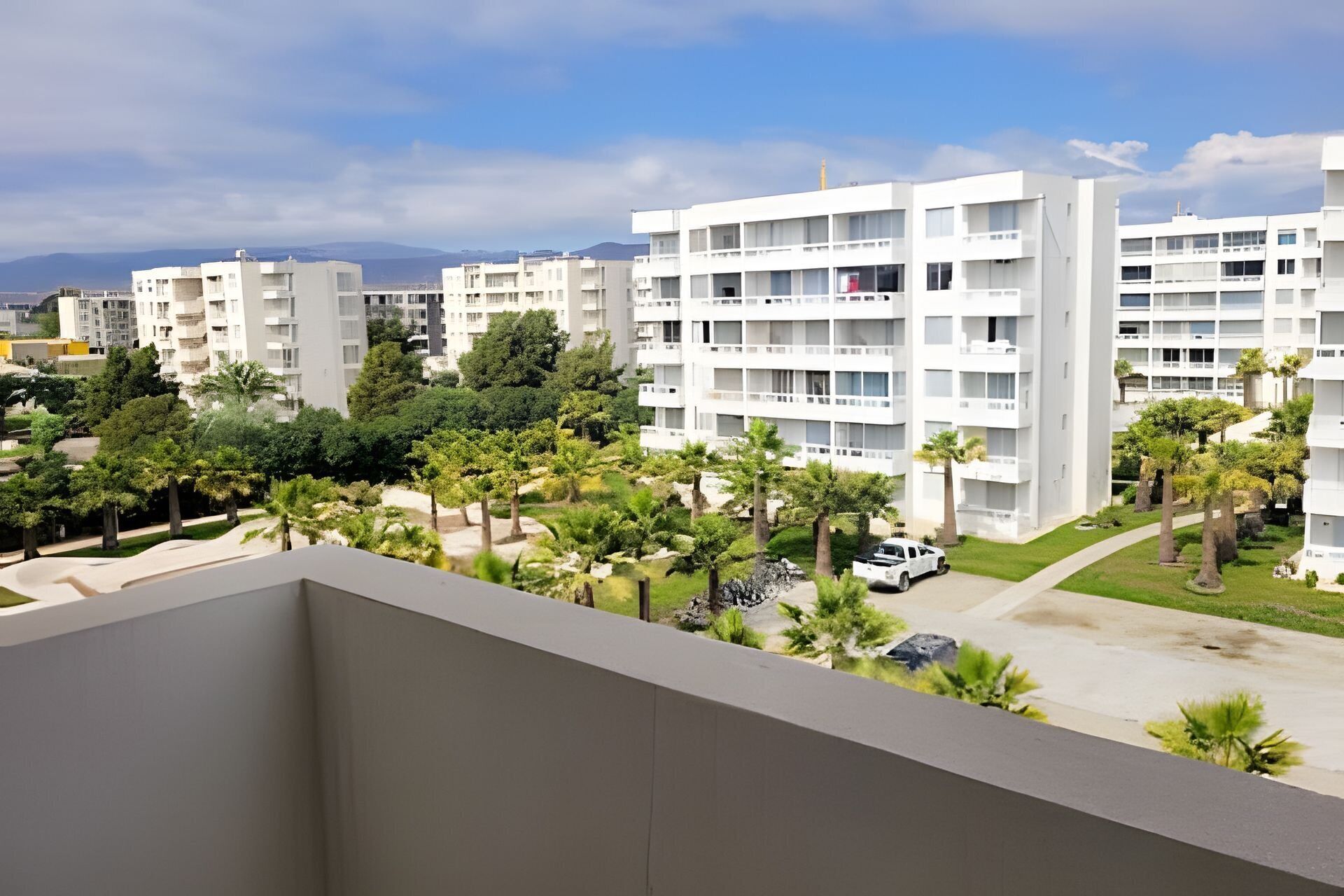 A modern apartment complex with multiple floors, balconies, and a landscaped garden area.