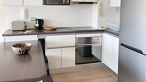 A modern kitchen with white cabinets, a stainless steel refrigerator, a microwave, and a coffee maker. - Dept. 10th Floor, Cond. Pacific II (La Serena)