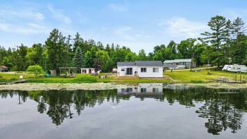 A lakeside property with a house, dock, and surrounding greenery.