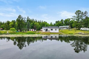 A lakeside property with a house, dock, and surrounding greenery.