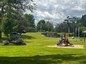 A park with a playground, a sign for Belvidere Township Roadside Park, and a clear sky.