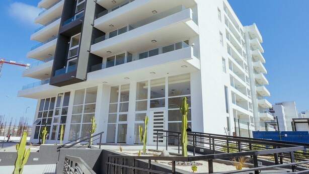 Un edificio moderno a più piani con balconi, ampie finestre e una gru edile sullo sfondo.