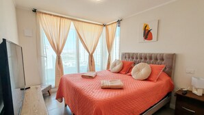 Una camera da letto con un letto grande, tende, una televisione e un quadro appeso al muro.