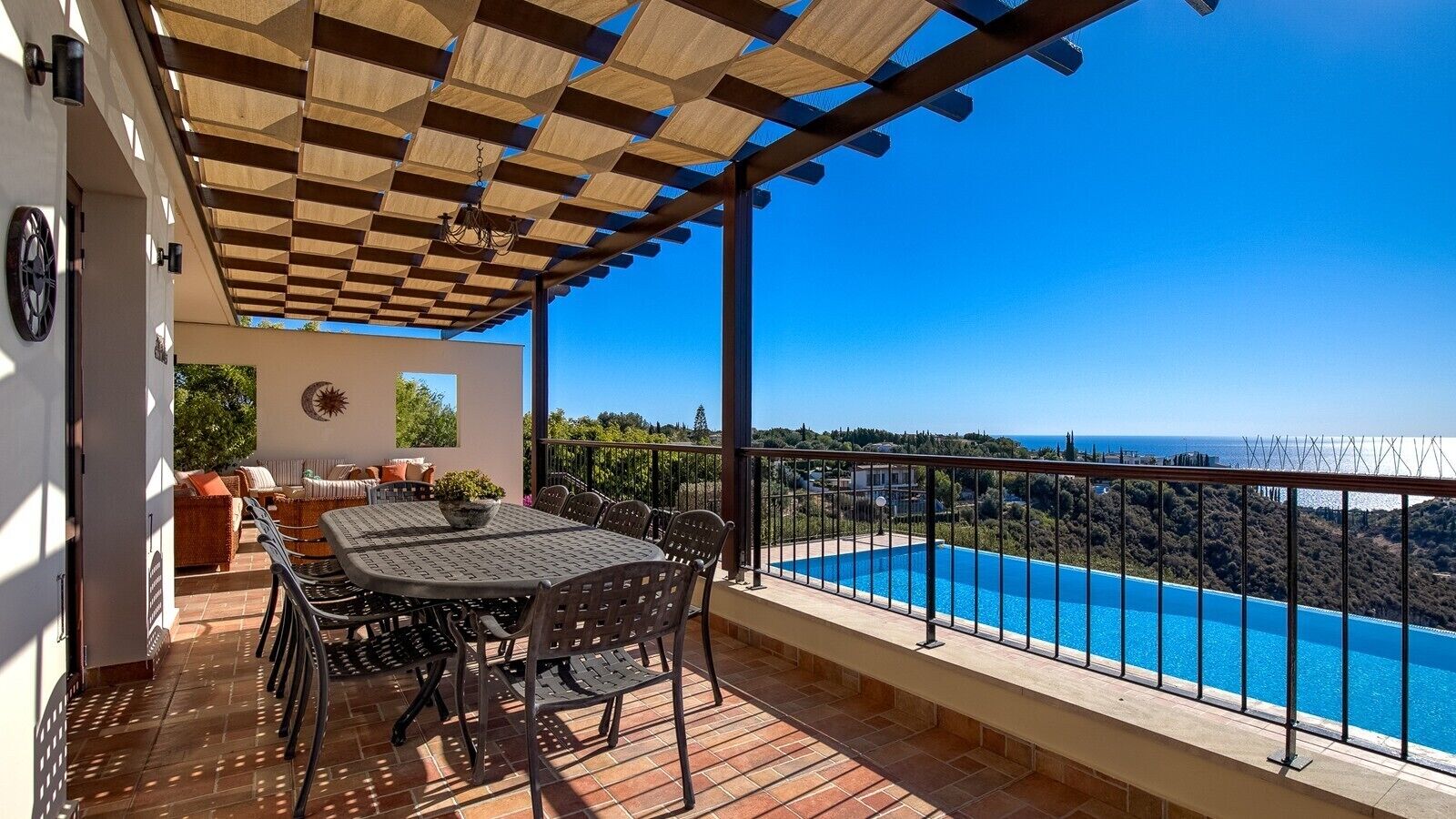 Un espacio al aire libre cubierto con piscina, una mesa y sillas, y vistas al mar.