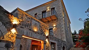 A stone building with a wooden door, a balcony, and exterior lighting.