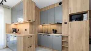 Eine moderne Küche mit Holzausstattung, einer integrierten Mikrowelle und einer Kaffeemaschine.