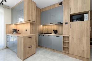 Eine moderne Küche mit Holzausstattung, einer integrierten Mikrowelle und einer Kaffeemaschine.