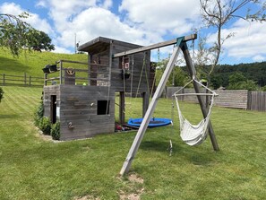 A wooden playhouse with a swing set and a hammock. - FAMILY HOME FOR 8 PEOPLE WITH A NORDIC HOT TUB—KIDS-FRIENDLY (Saint-Nabord)
