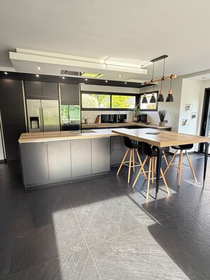 A modern kitchen with a large island, dark flooring, and pendant lighting. - FAMILY HOME FOR 8 PEOPLE WITH A NORDIC HOT TUB—KIDS-FRIENDLY (Saint-Nabord)