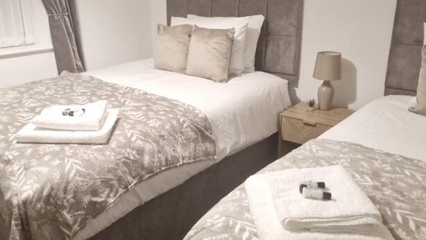 Une chambre double avec deux lits, une table de chevet, une lampe et un tableau au mur.