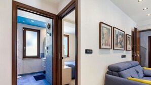 A modern interior with a sofa, a door leading to a bathroom, and framed artwork on the wall.