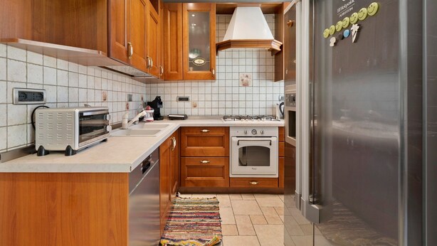 A kitchen with wooden cabinets, a stainless steel refrigerator, a built-in oven, and a toaster.