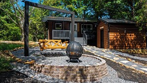 Un chalet rustique doté d’une terrasse en bois, d’un foyer et d’un banc.