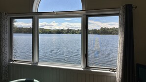 A room with a large window overlooking a lake, a curved skylight, and a chair. - Lost Lake Cottage

Munising/Wetmore (Munising Township)