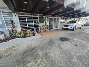 A building entrance with a bench, a Christmas wreath, and a parked white SUV. - LIS4B12 - SeaSide Beach II (Carolina)
