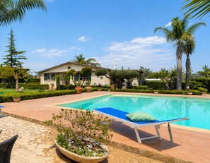 Ein Swimmingpool mit Liegestuhl und Topfpflanze.